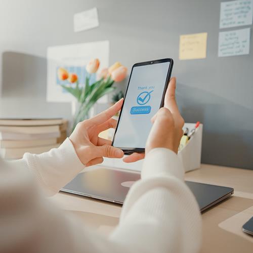 A Woman Using a Smartphone to Make Online Payment Solutions, with a Check Mark on the Screen