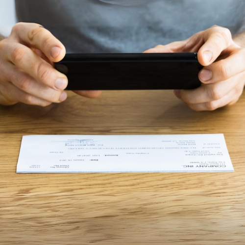 A Man Uses His Mobile Phone to Take a Picture of His Check for the Best Online Instant Check Cashing Service.
