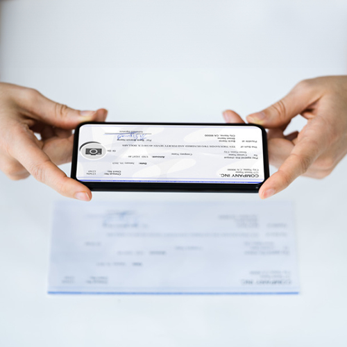 A Pair of Hands Holding a Smartphone Displaying an Image of a Check. Processing Cash Check Online