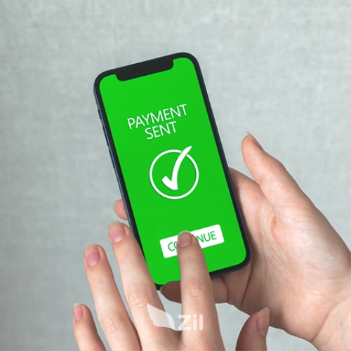 A Person Holding a Smartphone, Displaying a Confirmation Screen for a Successful Domestic Transfer Payment, Marked by a Green Checkmark