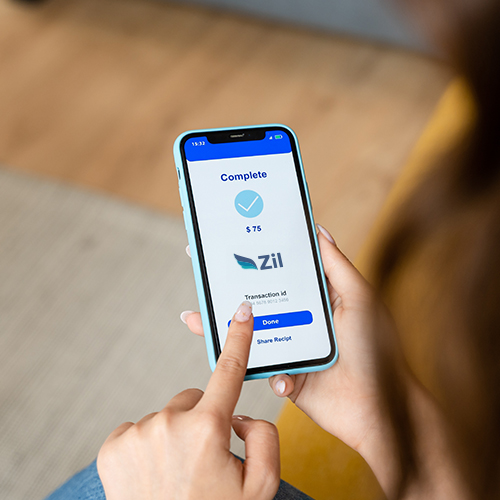 A Woman Holds a Mobile Phone, Using a Money Transfer Service to Send Funds