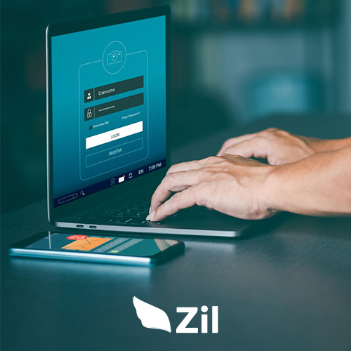 A Person's Hands Are Typing on a Laptop Keyboard, with a Login Screen for Zil Business Checking Account Displayed on the Laptop's Monitor.